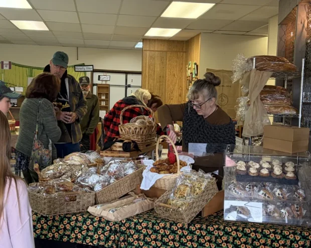 horsefly-market-bakery-counter Vendors and customers at the market bakery counter, with baskets of bread and a display case of pastries